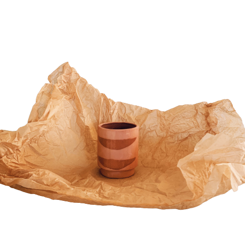 A cup sitting on top of a piece of brown paper in a garden center.